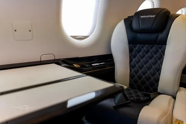 A comfortable seat and table inside the Pilatus PC-12 aircraft cabin.
