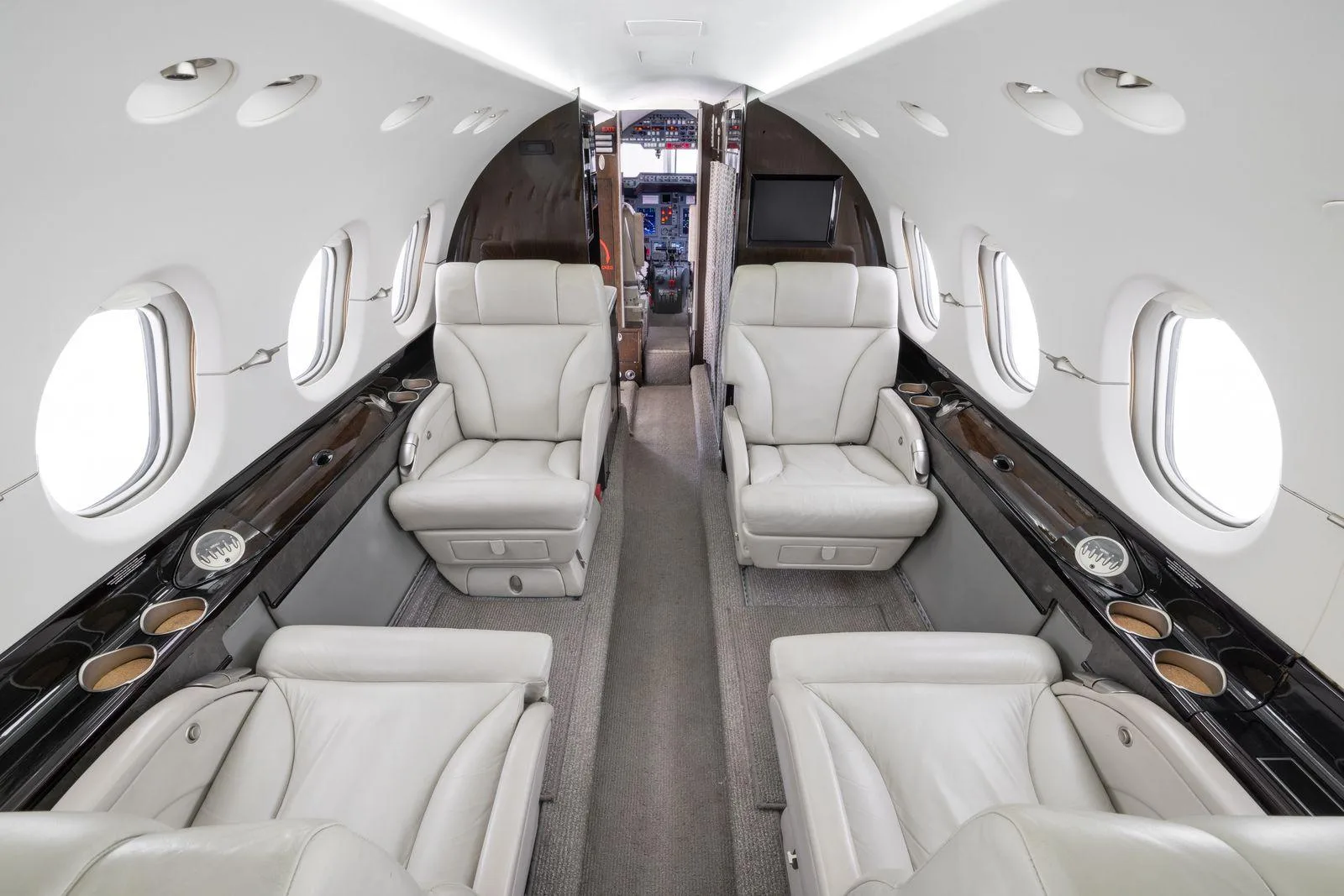 A view of the aircraft's cabin interior featuring light leather seats and a central aisle.