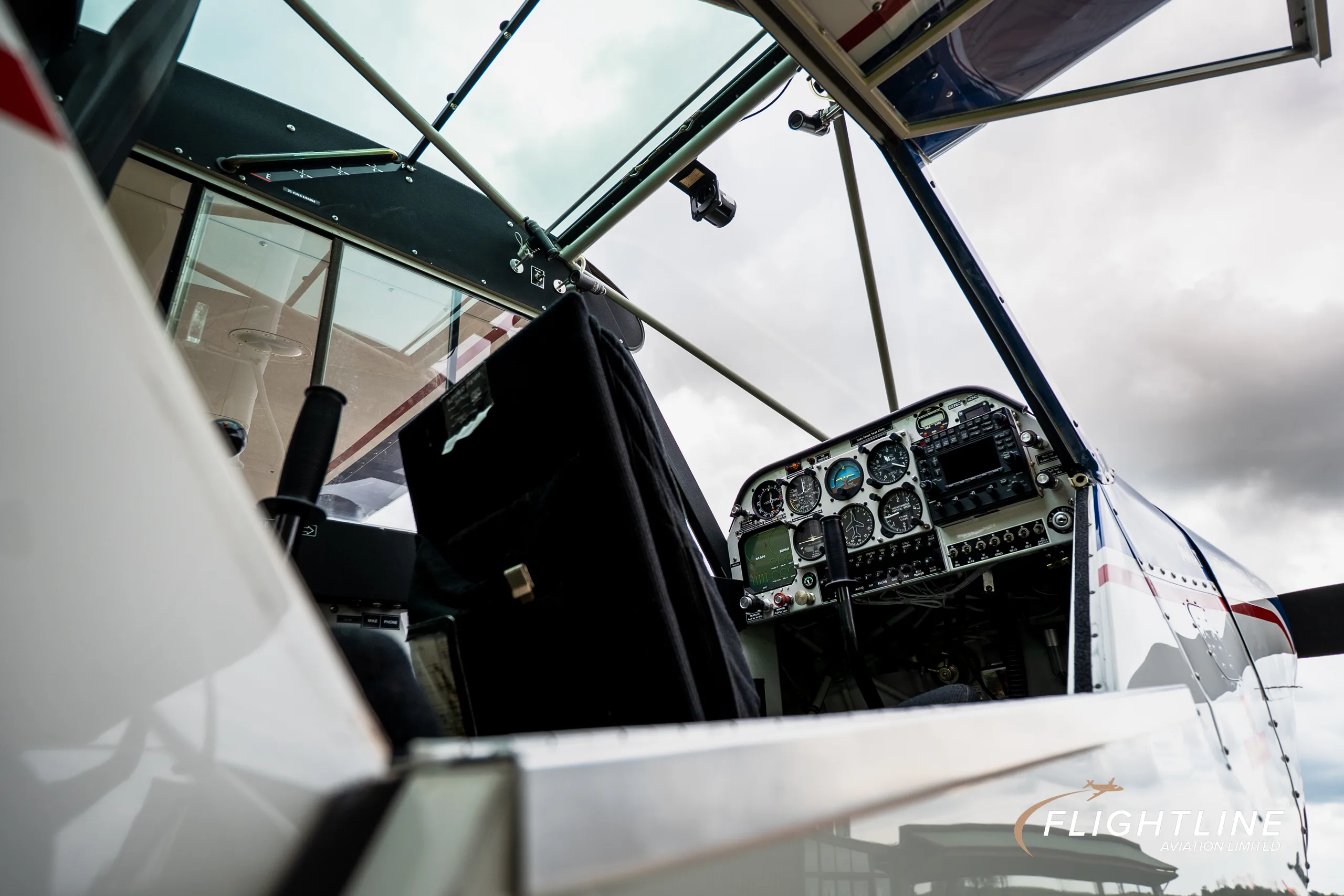 A close-up view looking into the cockpit of the Aviat Aircraft Husky A-1B, showing the instrument panel and a black seat.