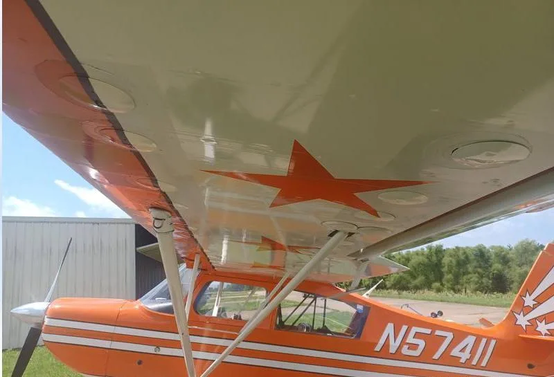 An underside view of the wing of the orange N57411 aircraft, showing a large red star decal and the fuselage.