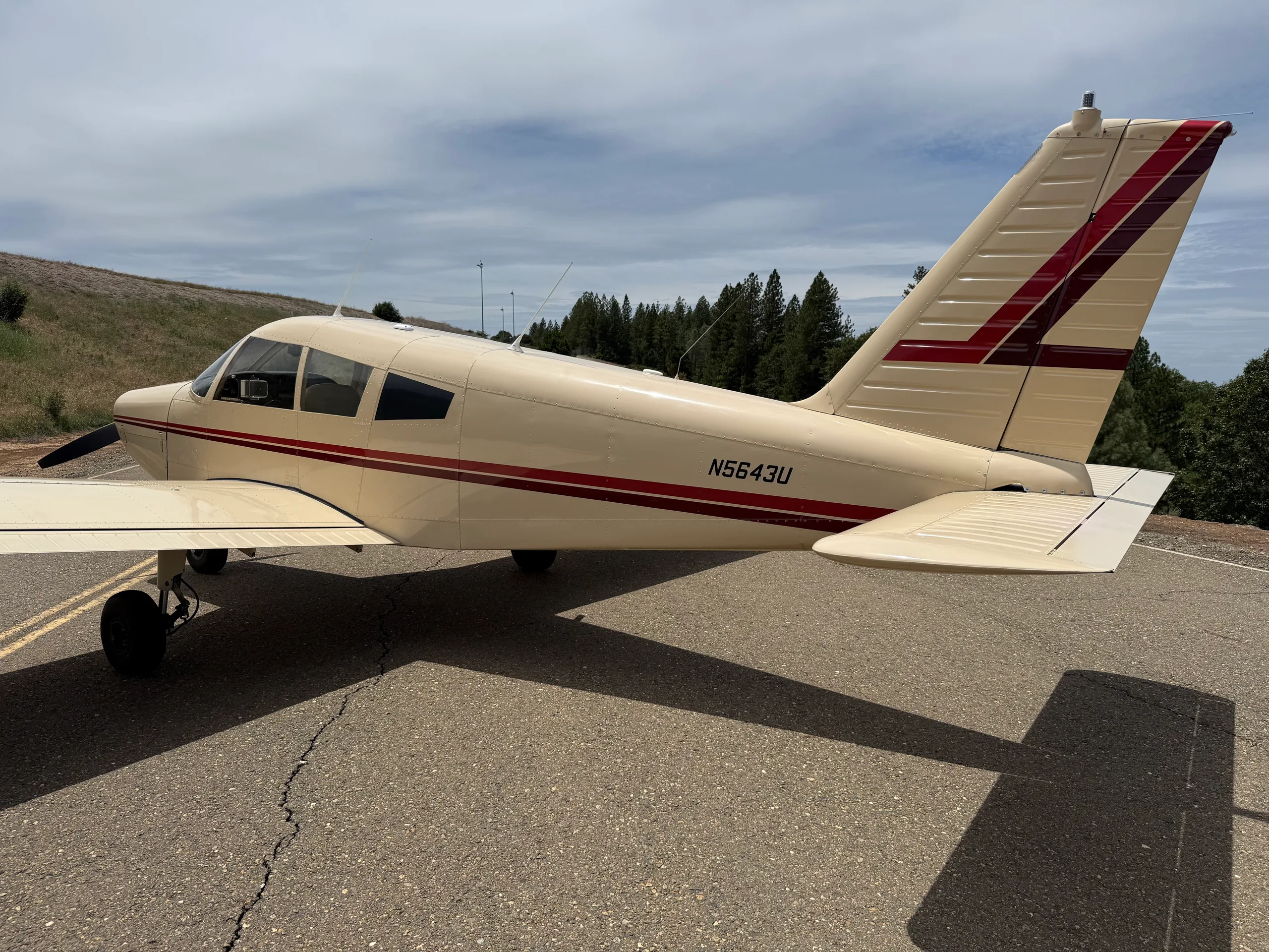Rear-side view of the N5643U aircraft, showing its cream and red tail on an asphalt surface.