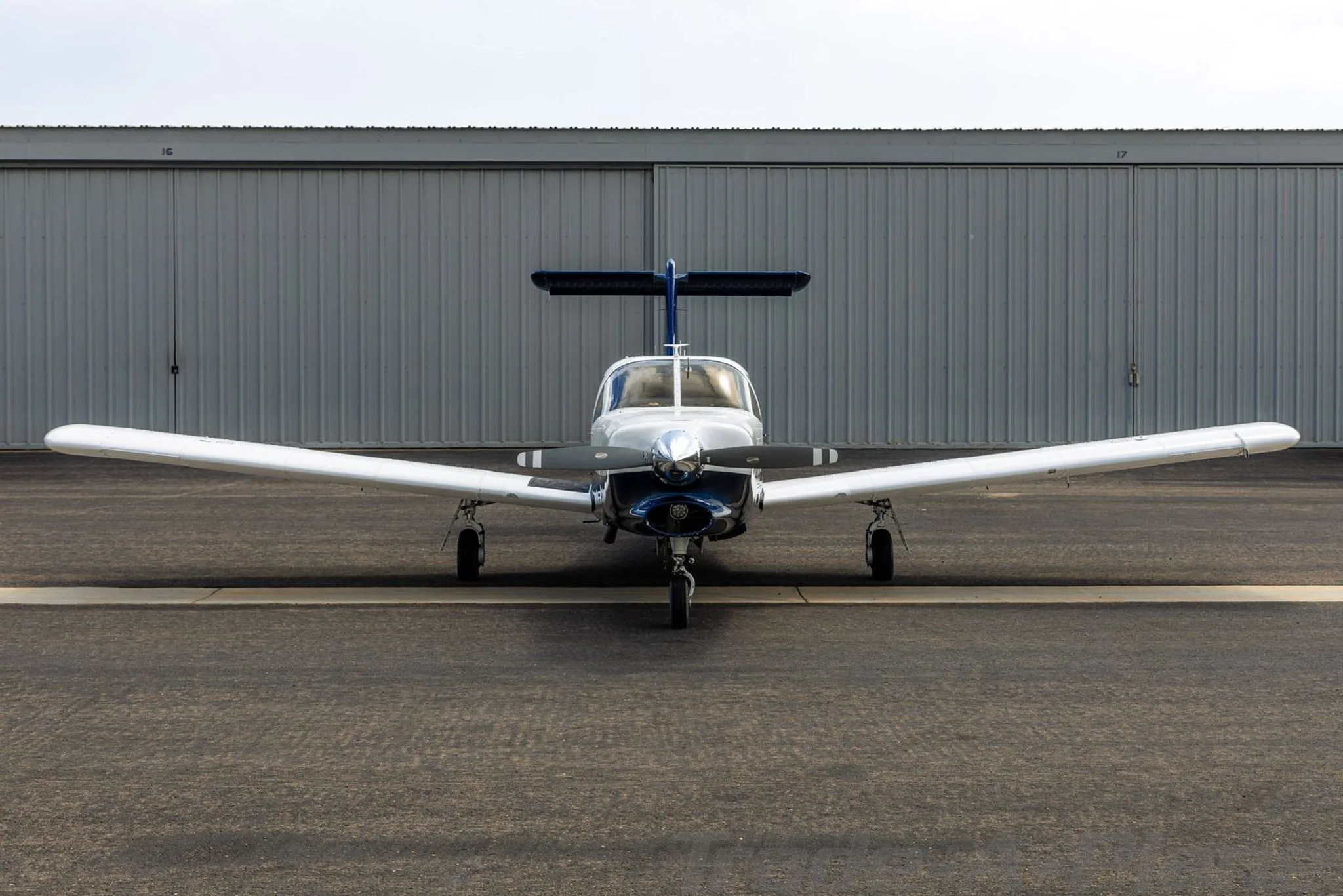 A head-on view of the white and blue Piper aircraft N318PK parked on an airport tarmac.