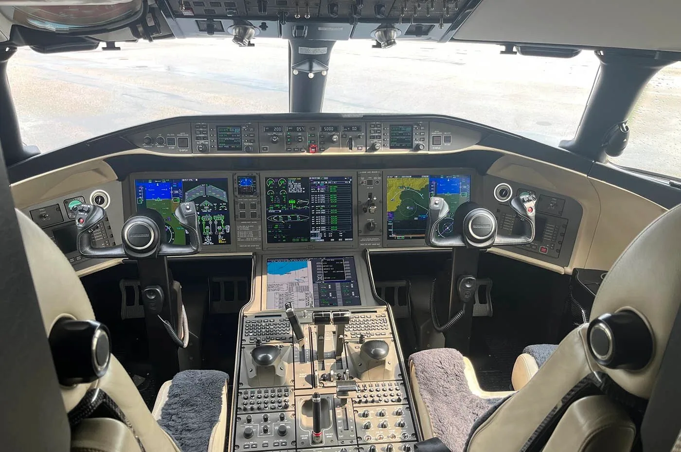 The modern cockpit of a business jet, featuring multiple digital displays and control panels.