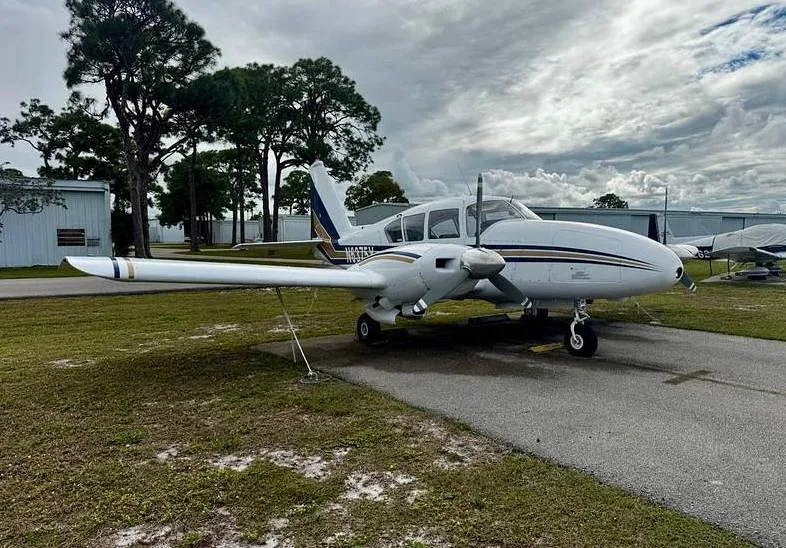 A white twin-engine aircraft with blue and gold stripes, registration N6375Y, parked on an asphalt ramp at an airfield.