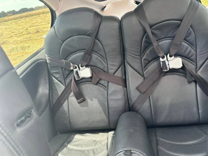 View of the two black leather rear seats with seatbelts in the aircraft cabin.