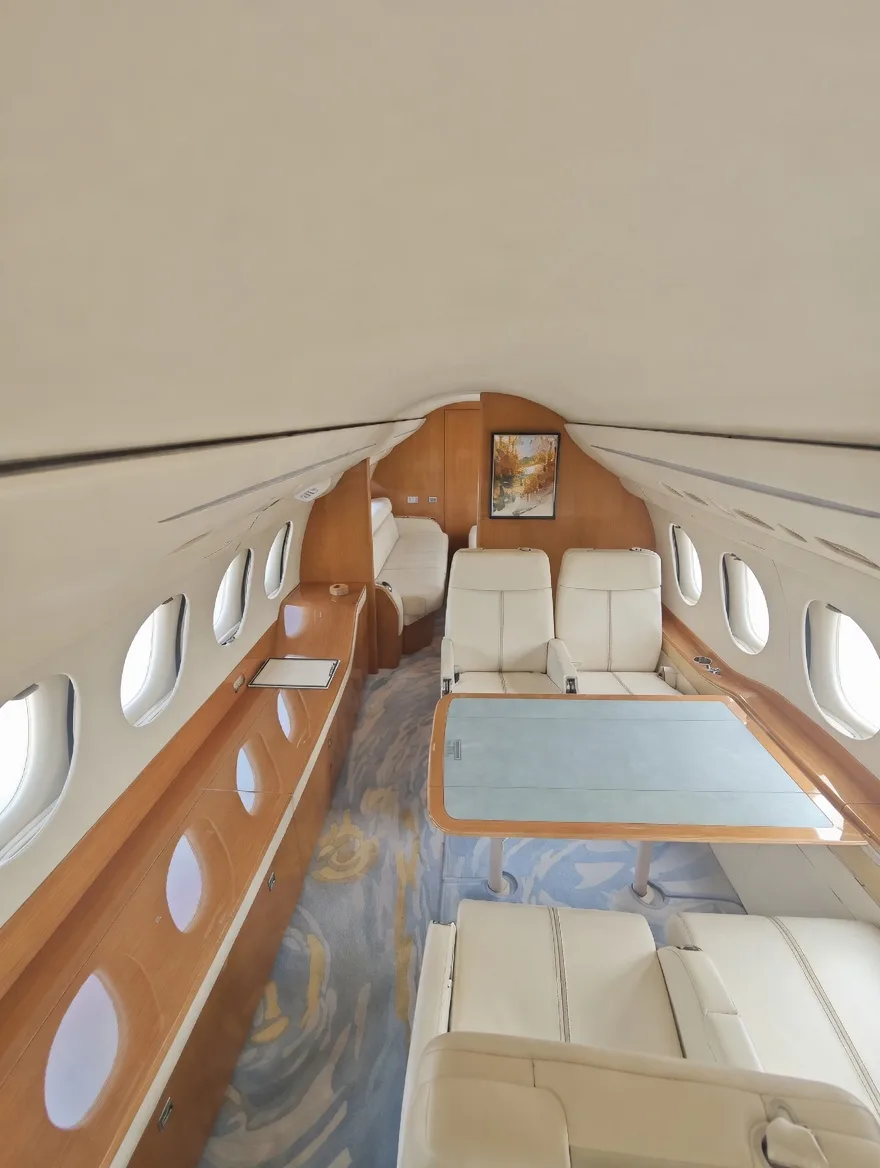 A long view of an aircraft cabin with a dining table, cream leather seating, and a patterned carpet.
