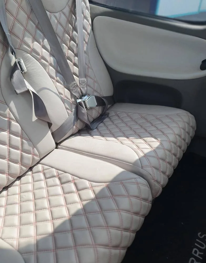 A close-up view of the light-colored quilted leather interior seats of an aircraft with red stitching.