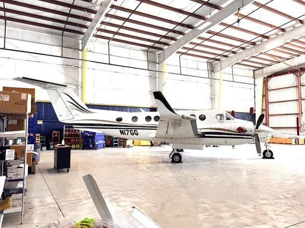 The N17GG Beechcraft King Air with black and gold stripes is parked inside a hangar.