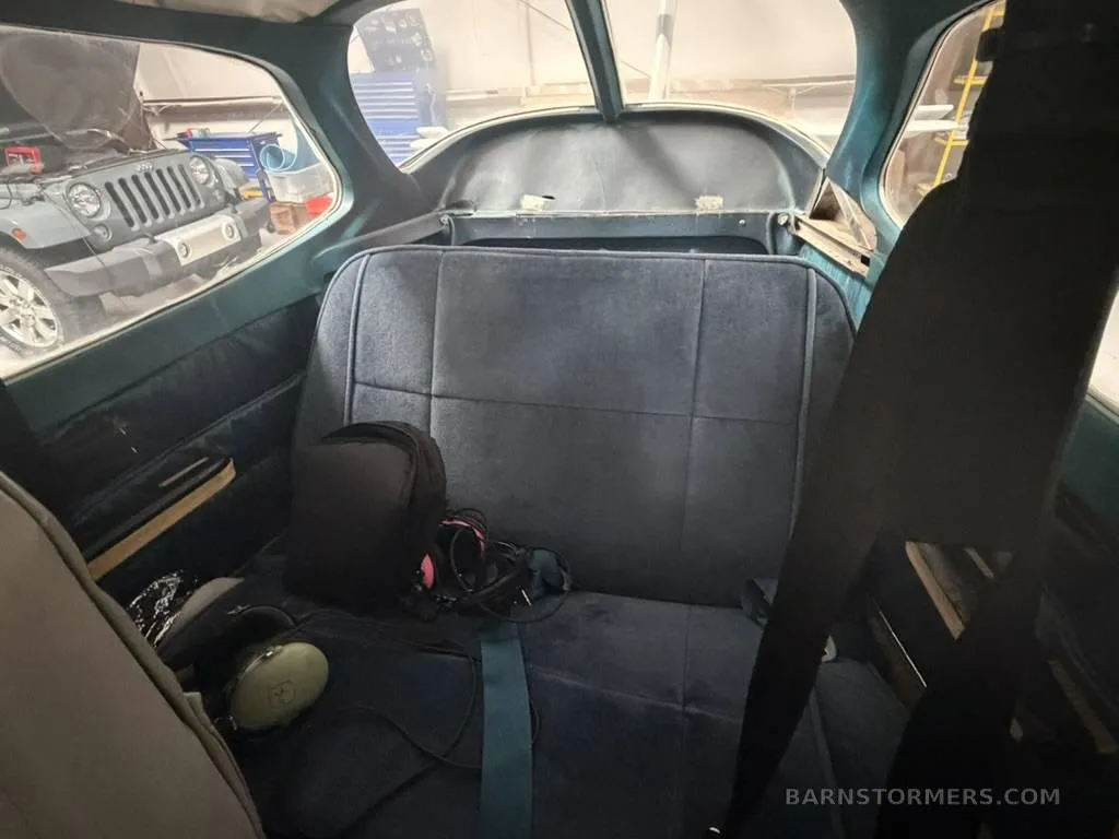 The rear cabin seats of a Cessna 172, upholstered in blue fabric, with headsets and a bag on them.