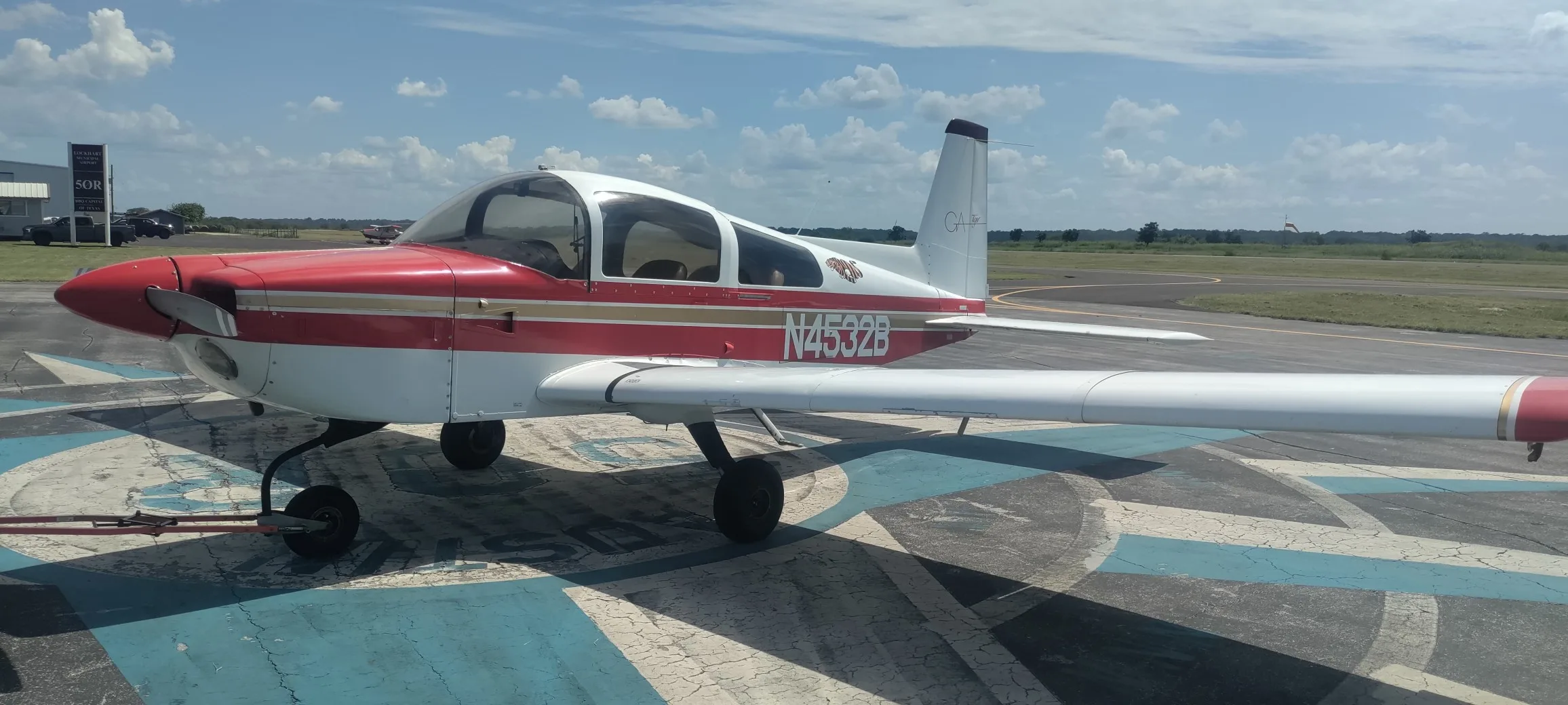 A red and white Gulfstream American GA-7 Cougar aircraft, N4532B, parked on an airfield with a blue and white pattern.