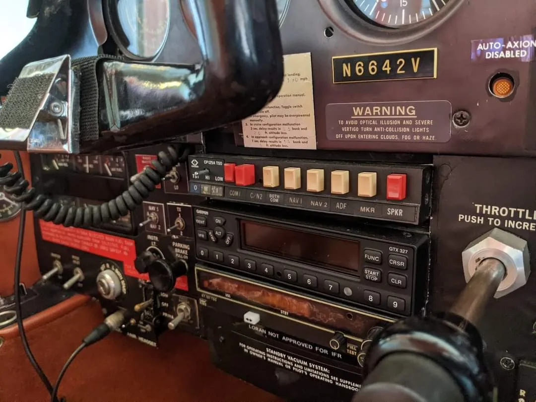 A close-up view of the avionics stack and warning labels in the cockpit of a Bellanca aircraft.