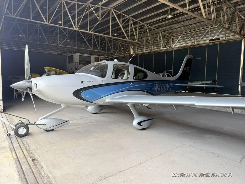 A front-side view of a white and blue Cirrus SR22 aircraft, registration N400VT, parked inside a hangar.