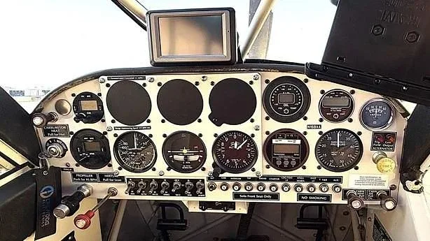 The aircraft's cockpit features an instrument panel with multiple gauges, switches, and a mounted GPS unit.