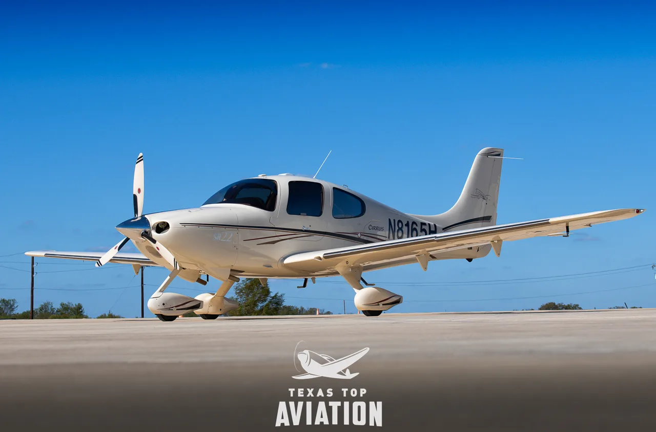 A light-colored Cirrus SR22, registration N816SH, is parked on the tarmac under a clear blue sky.