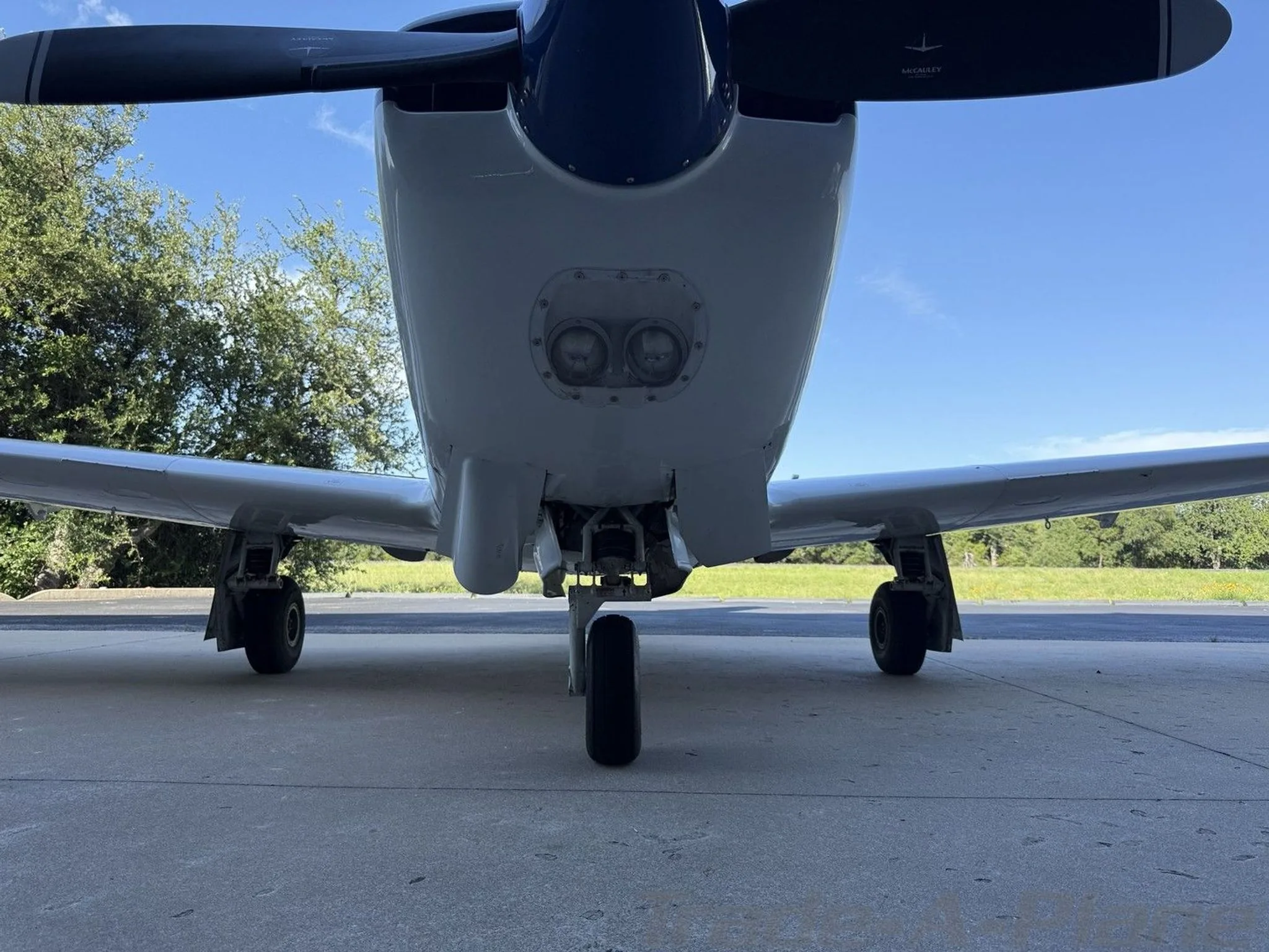 An underside view of the white and blue single-engine aircraft, N1156G, showing its landing gear and exhaust.