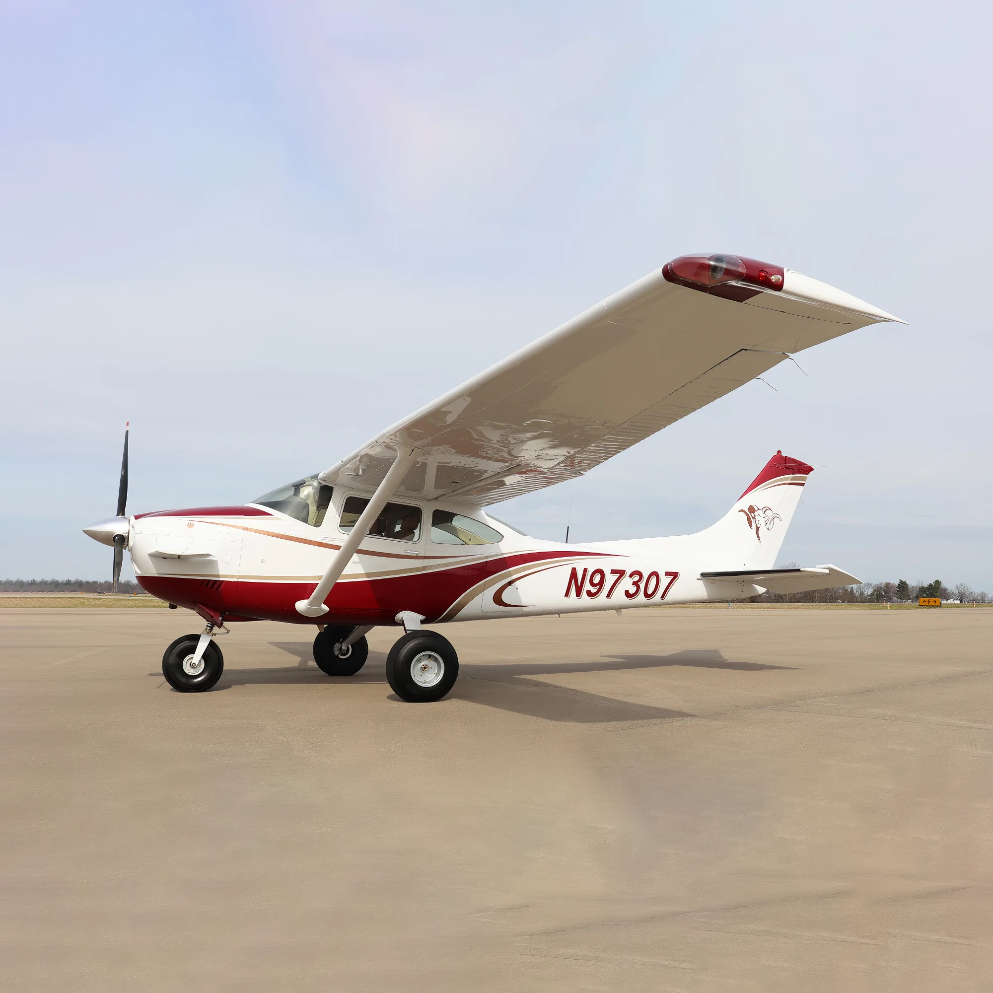 A white and red single-engine high-wing aircraft, N97307, parked on an airfield under a partly cloudy sky.