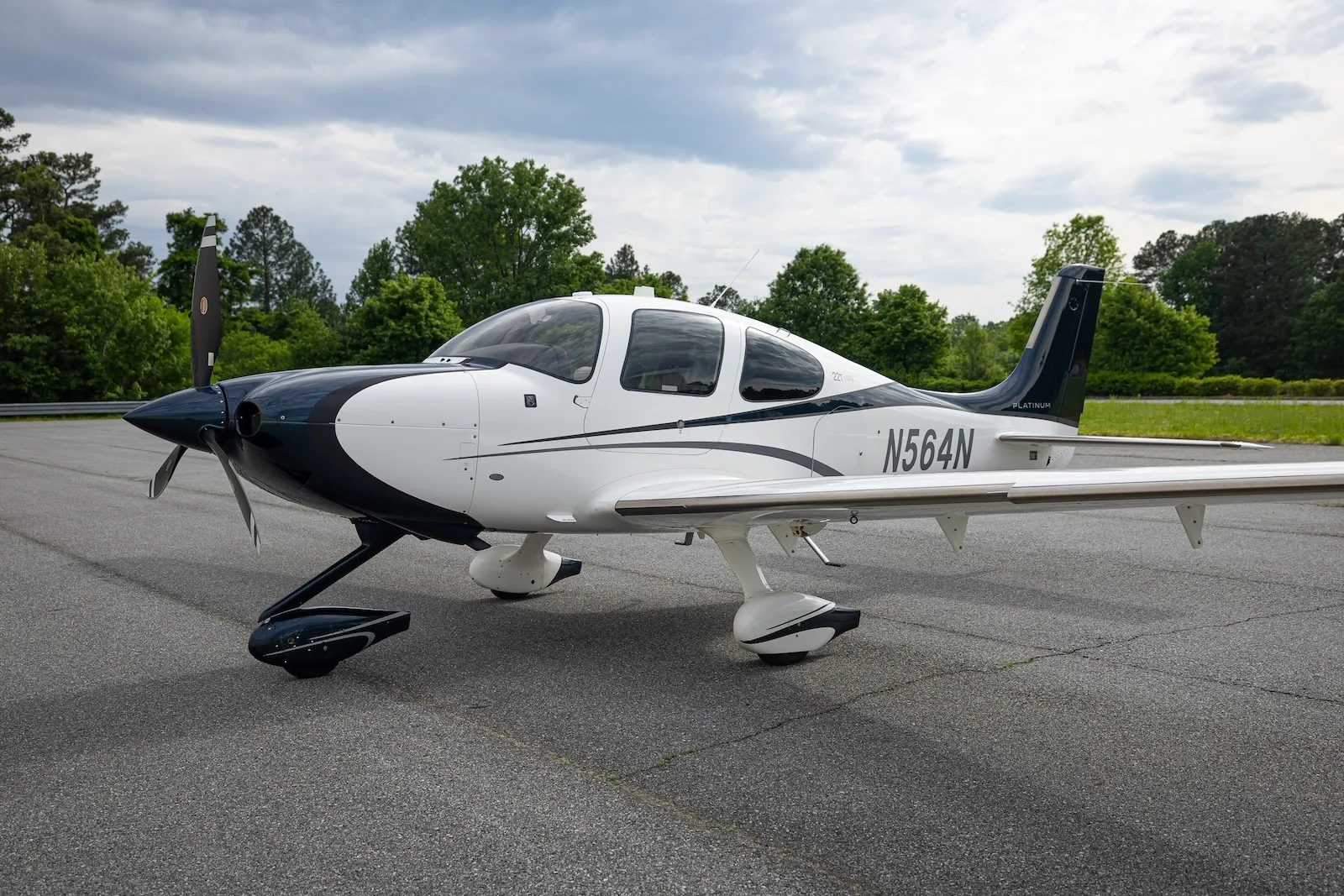 A white and dark blue Cirrus SR22T aircraft with registration N564N parked on an asphalt ramp.