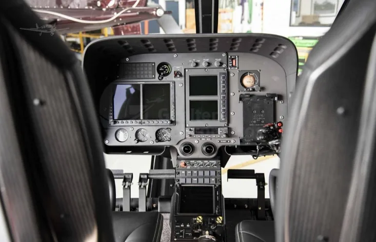 The cockpit of a helicopter showing the instrument panel with multiple screens and controls.