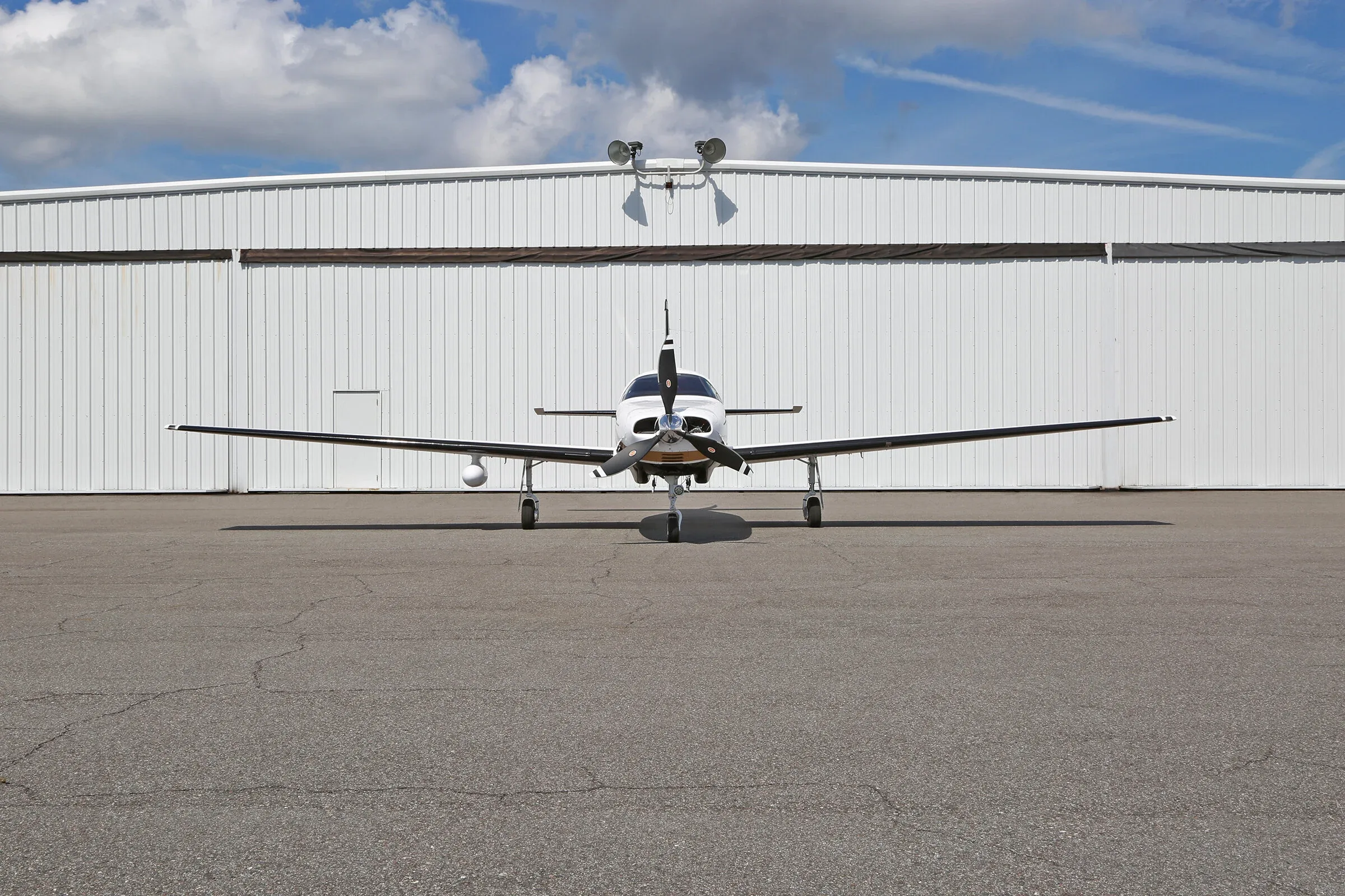 Front view of a Piper Mirage aircraft parked in front of a hangar.