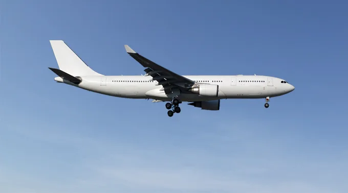 An all-white wide-body aircraft with landing gear extended, flying against a clear blue sky.