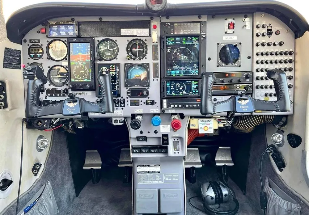 The cockpit of a single-engine aircraft, N91727, features a mix of analog gauges and modern digital displays, with dual yokes.