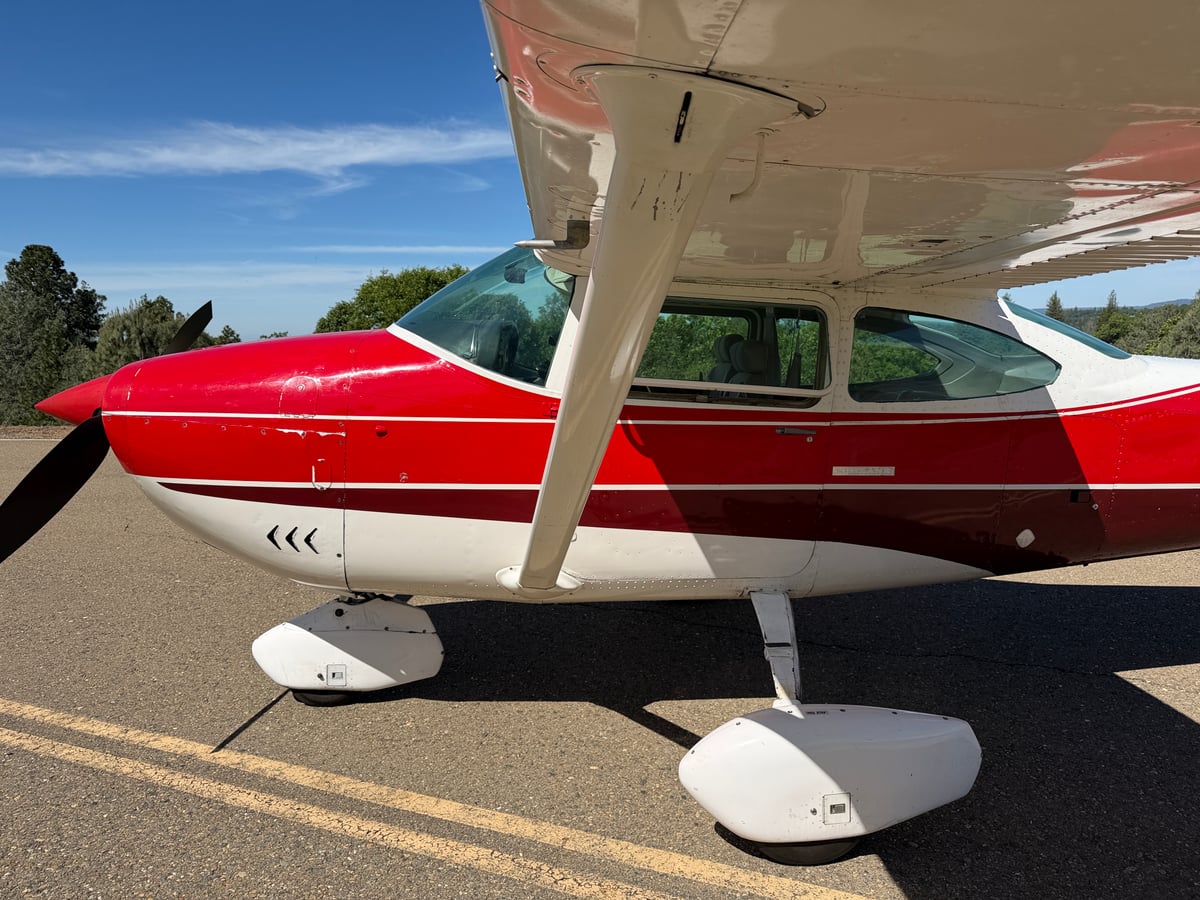 The red and white Cessna Skylane N71589 is parked on the tarmac under a blue sky.