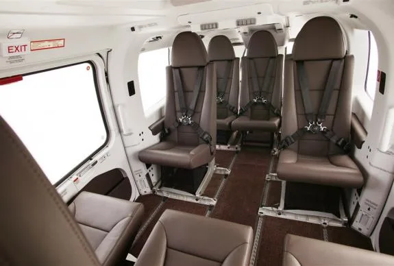 Interior view of the helicopter cabin with brown leather seats and seatbelts.