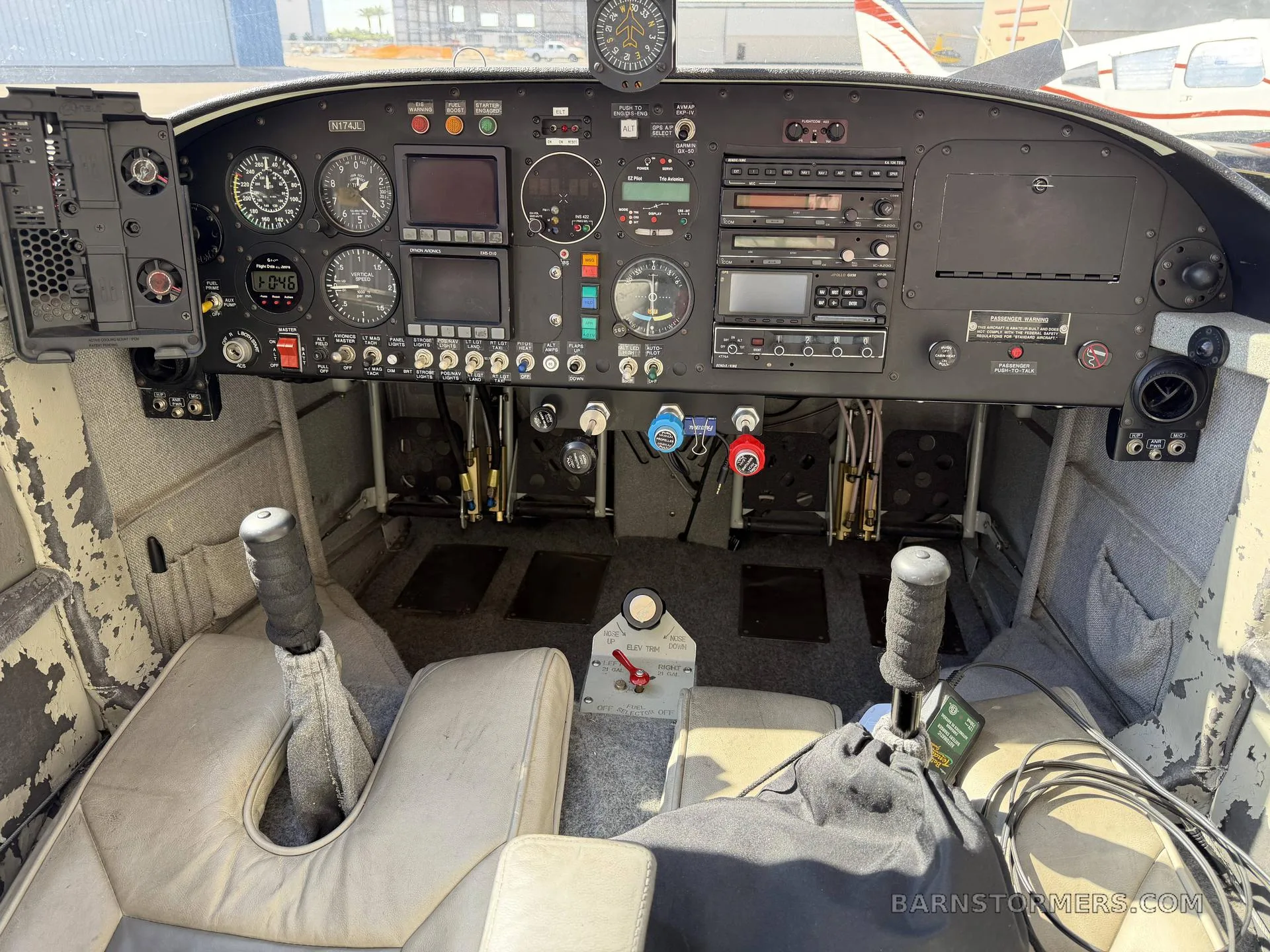 The cockpit of a Vans RV-7A aircraft, showing the instrument panel with various gauges and radios, and two front seats.