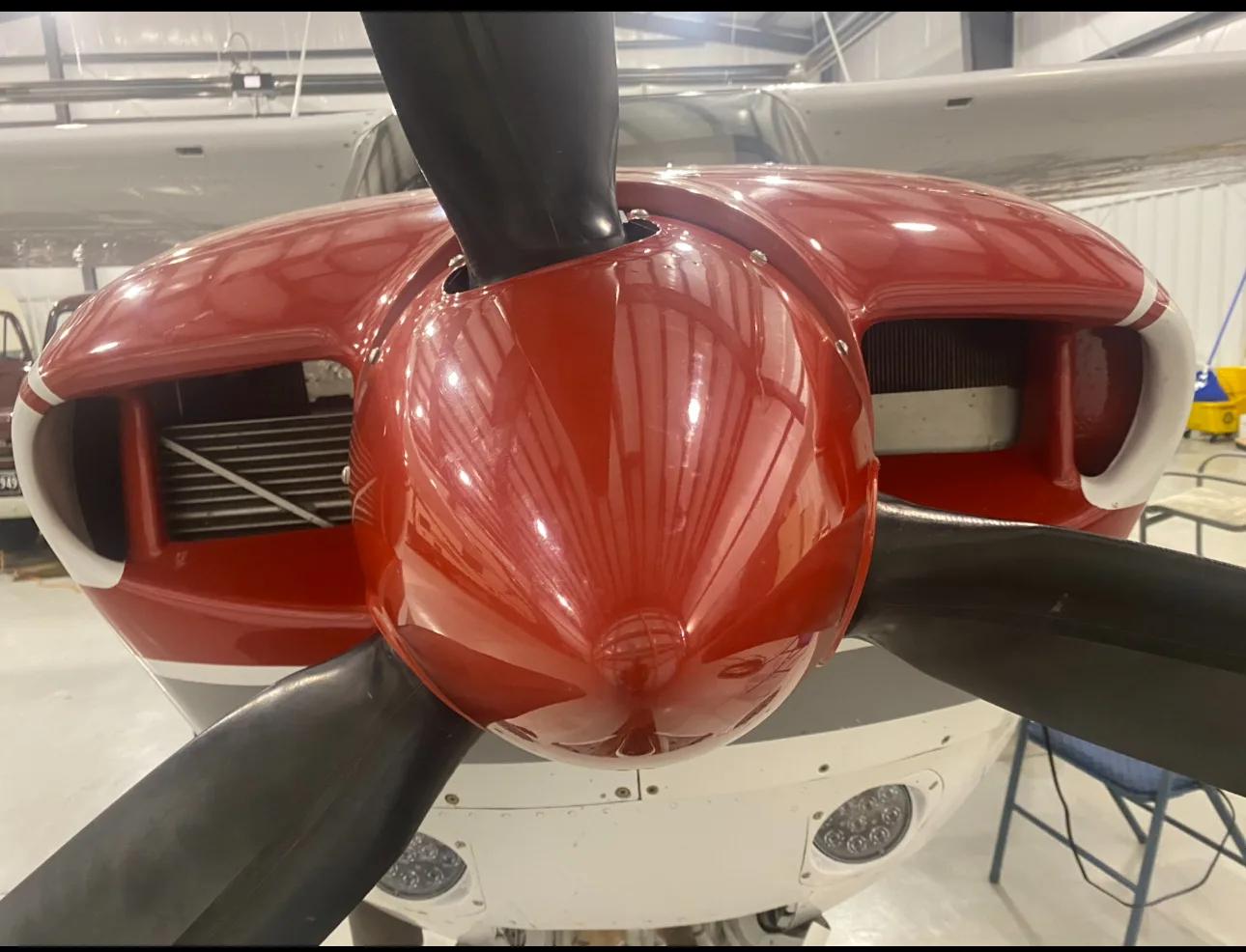 Close-up of the red nose cone and propeller of a white and red aircraft.