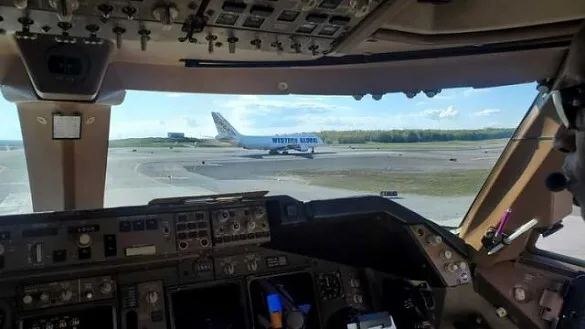 View from a cockpit showing the instrument panel and another "Western Global" Boeing 747 cargo aircraft on the tarmac in the distance.