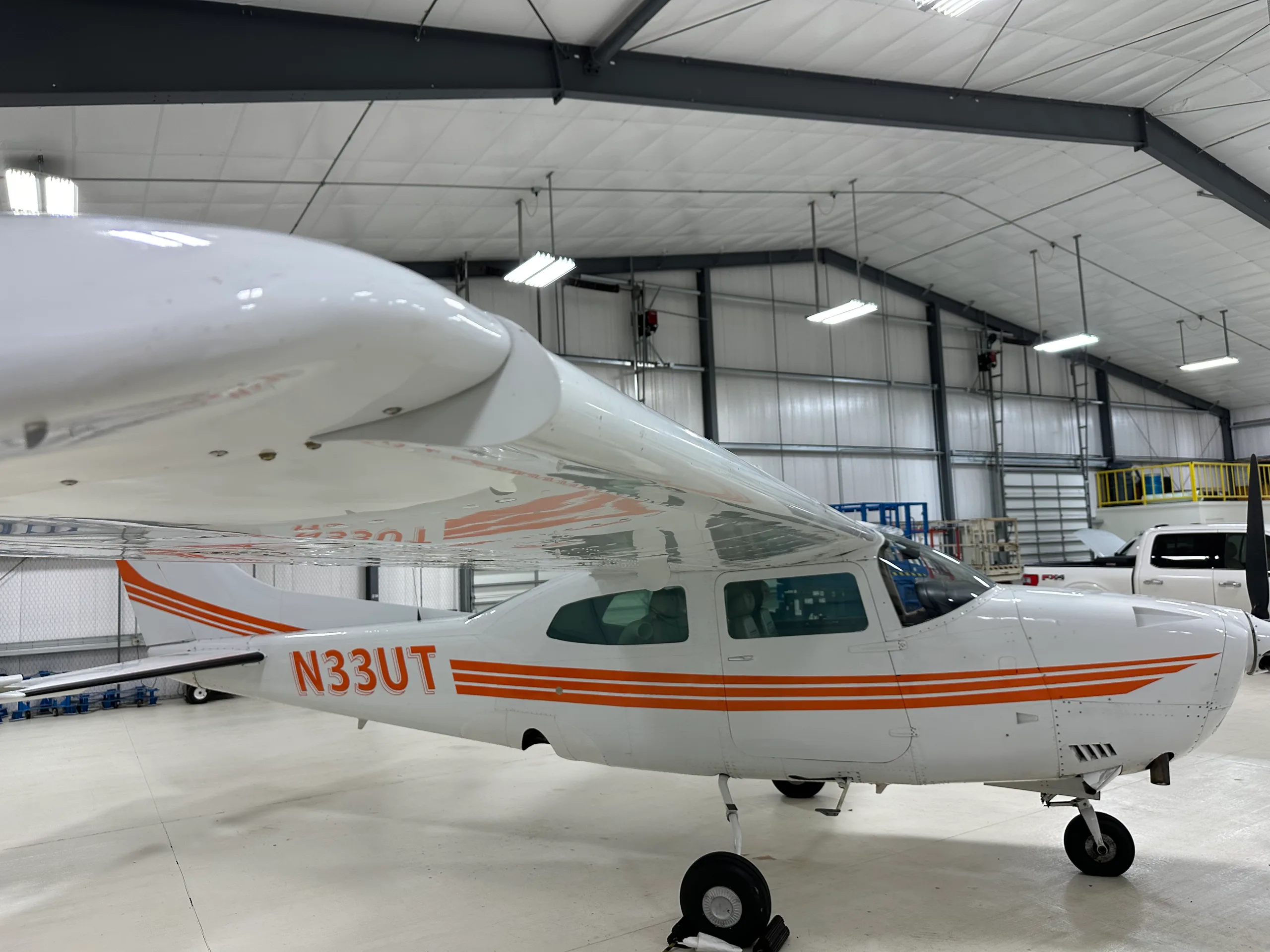 A Cessna 206 Stationair aircraft with orange stripes parked in a hangar.