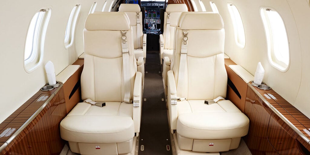The interior of the aircraft features cream-colored leather seats and wood trim.