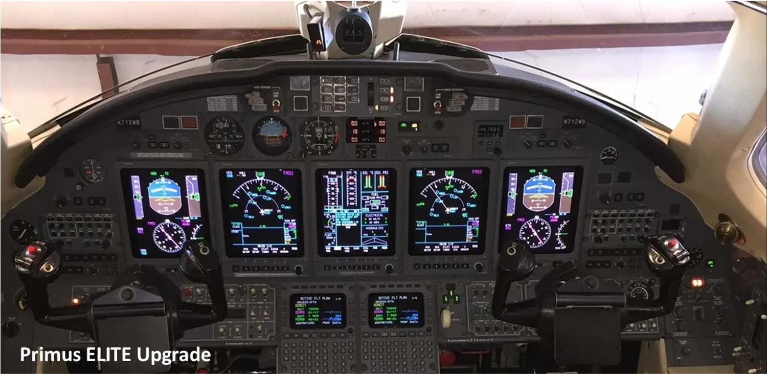 The cockpit of a business jet, showing a modern instrument panel with multiple digital displays and control yokes, with registration N712WB visible.
