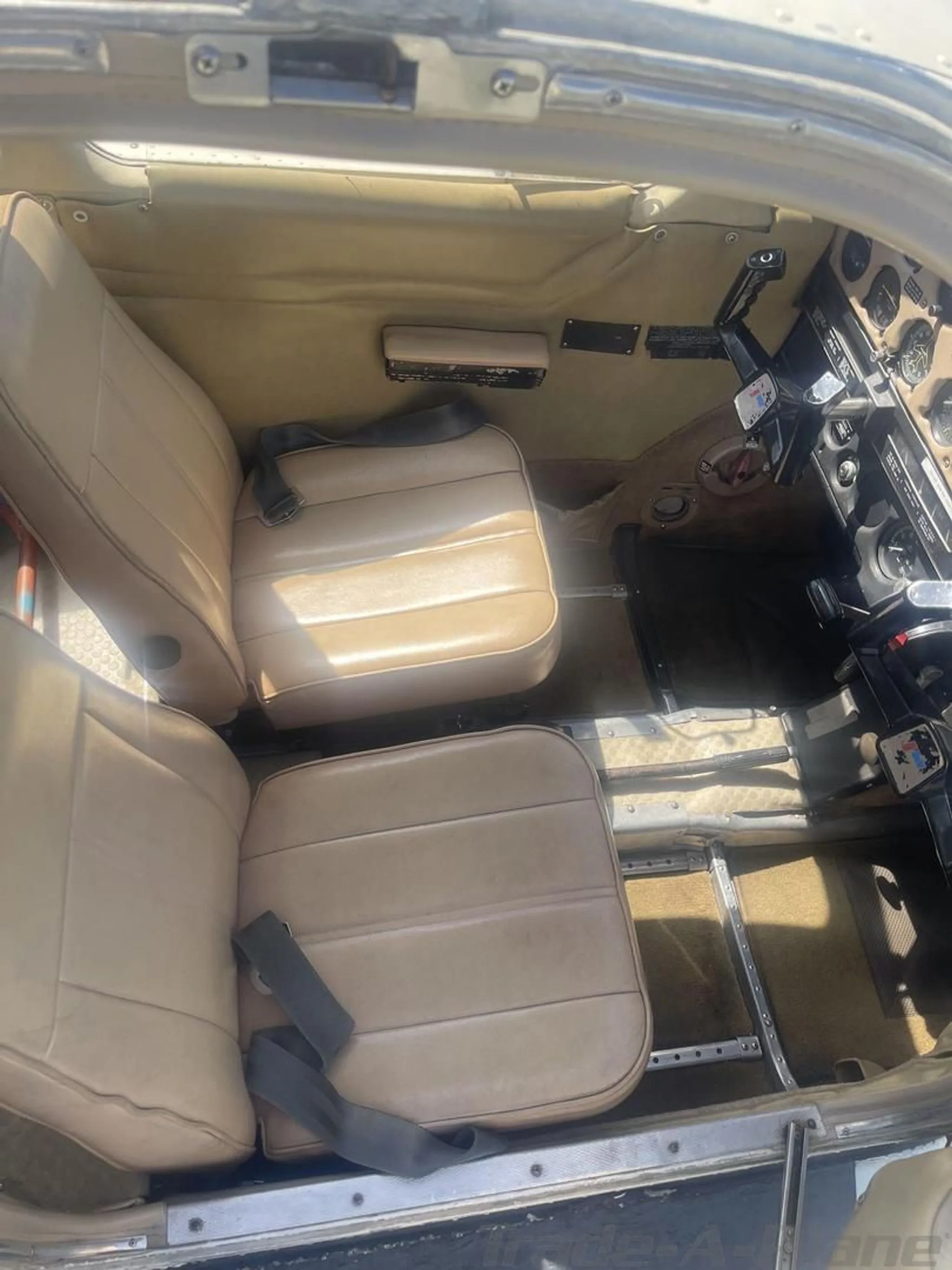 View of the aircraft's tan interior cabin with two front seats and visible floor rails.