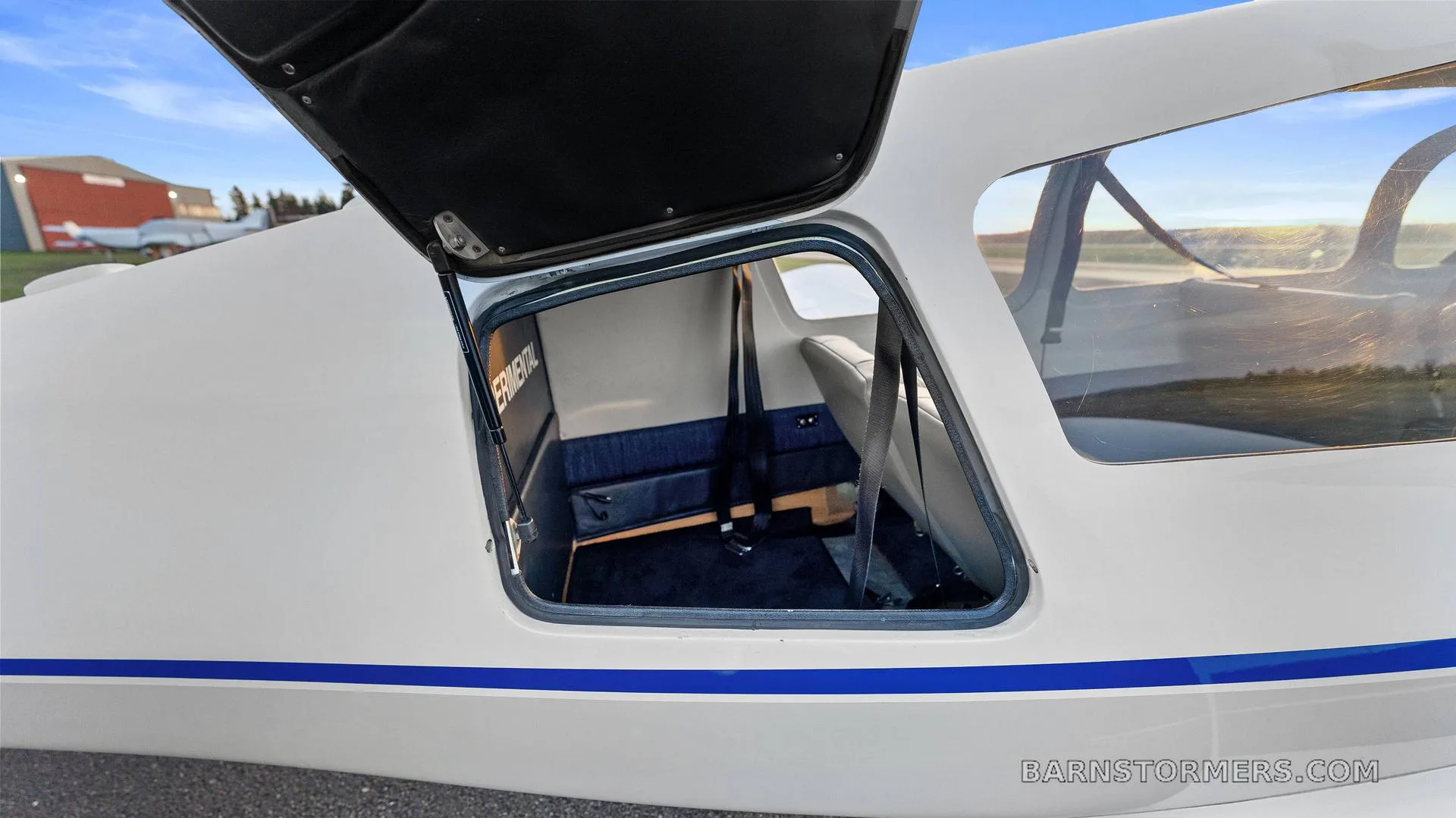 An open baggage compartment door on the side of the white aircraft, revealing the rear interior cabin space.