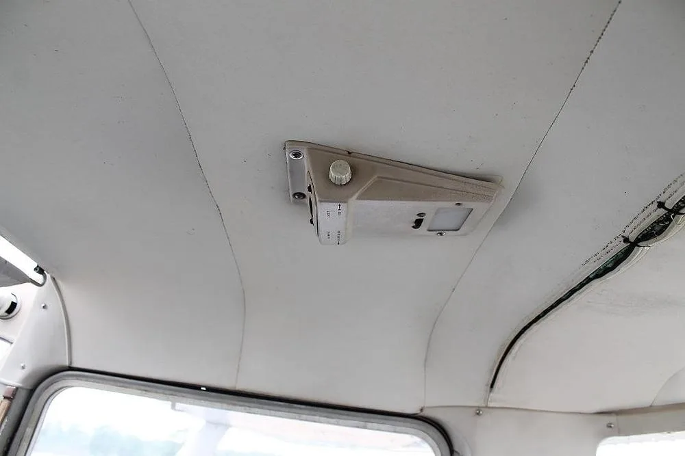 A view of the white ceiling of an aircraft cabin with an overhead light and vent.