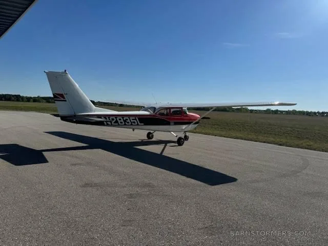 A red and white Cessna 172, registration N2835L, parked on an asphalt runway under a clear blue sky.