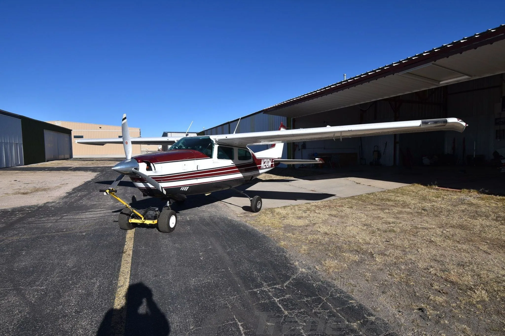A Cessna 210K parked in front of a hangar.