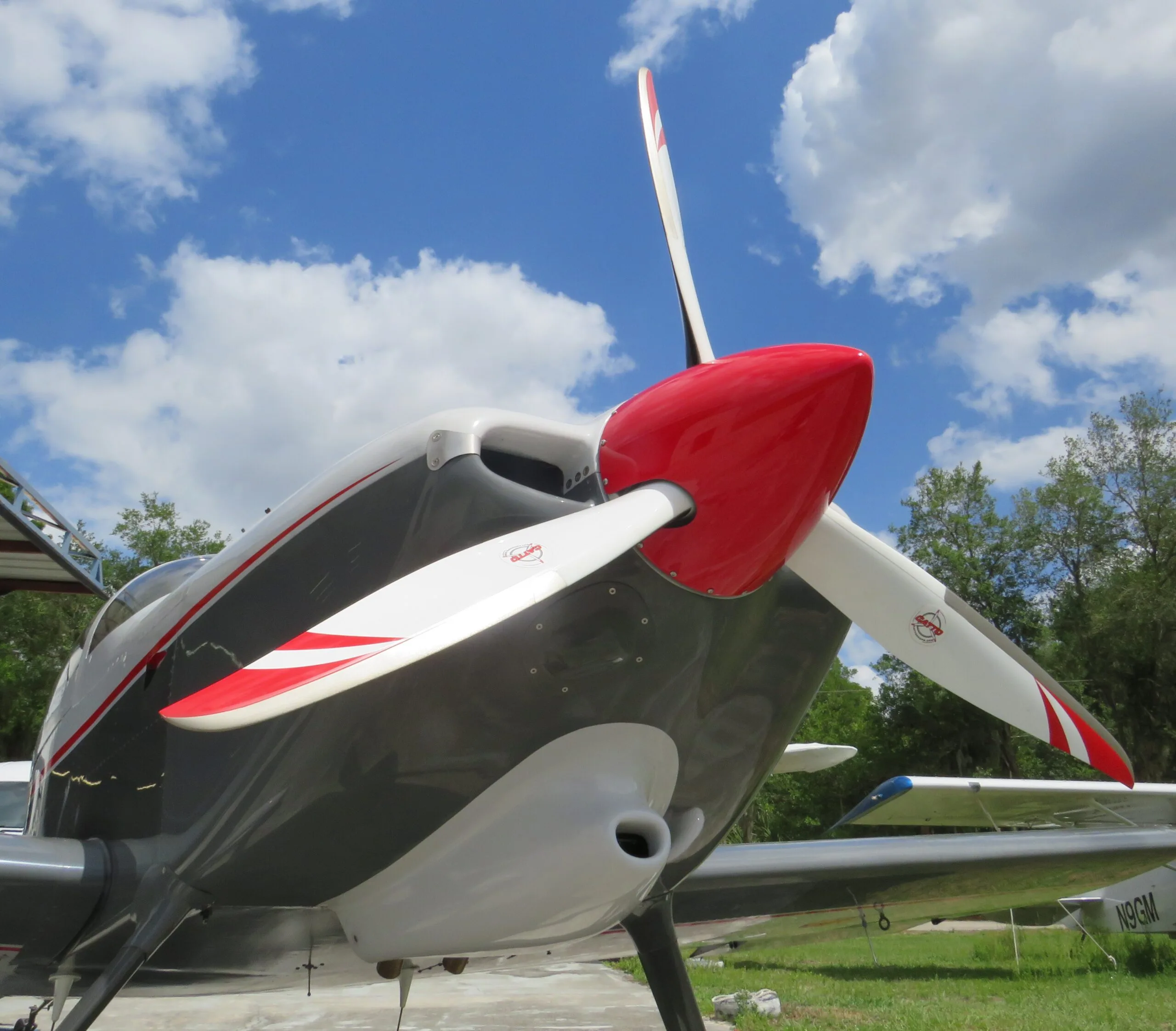 Close-up view of the propeller and nose of a white and grey aircraft with a red spinner.