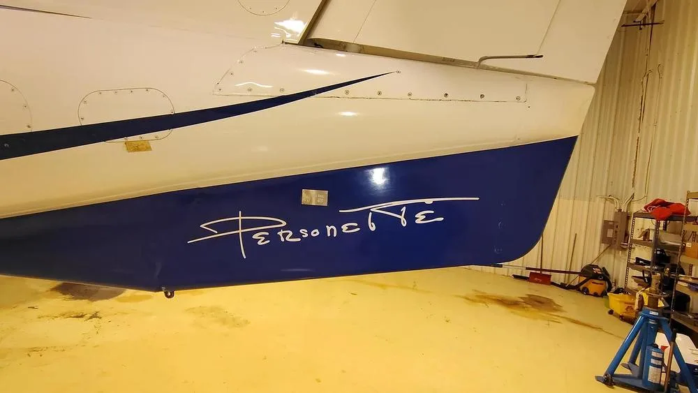 A close-up of the blue tail section of a Learjet 35A, showing 'Personette' in white script.