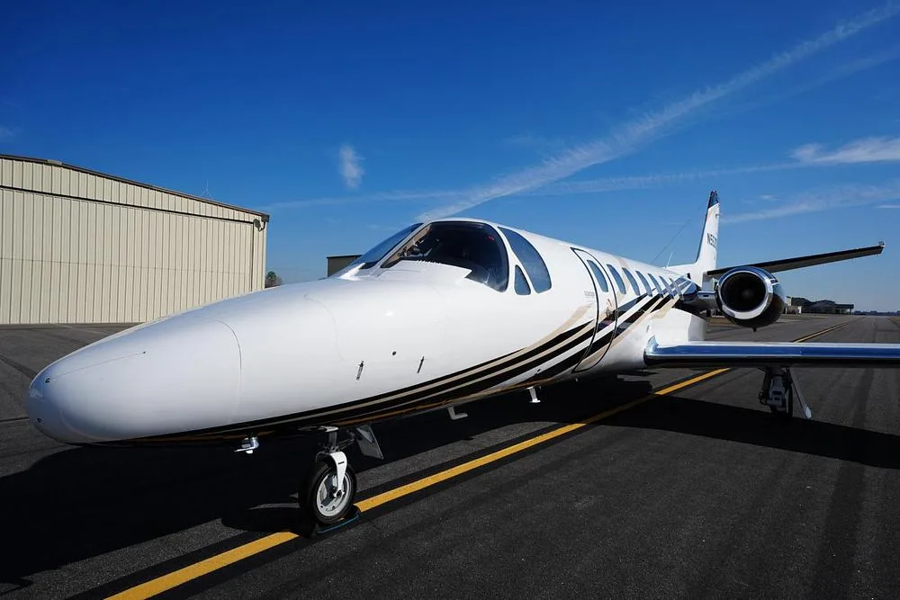 A front-quarter view of the white Cessna Citation Encore business jet N560CB, showing its nose and cockpit.