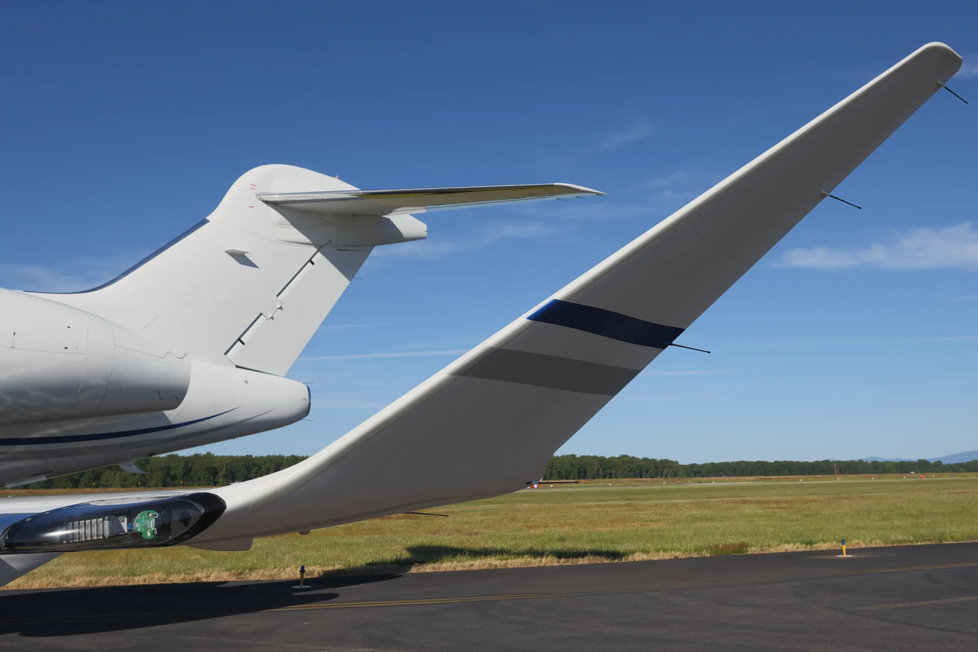 A close-up view of the white T-tail and winglet of a business jet with blue and gray stripes.