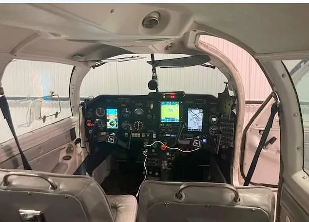 Wider view of the aircraft's cockpit showing the instrument panel, controls, and front seats.