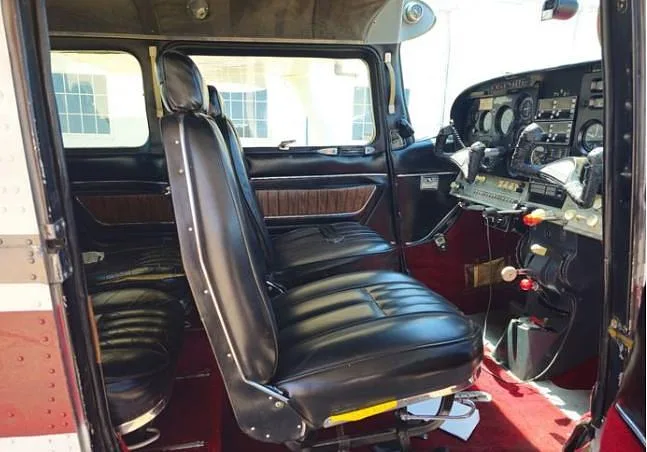The interior cabin of a Cessna 210 Centurion aircraft, showing black leather seats and a glimpse of the instrument panel.