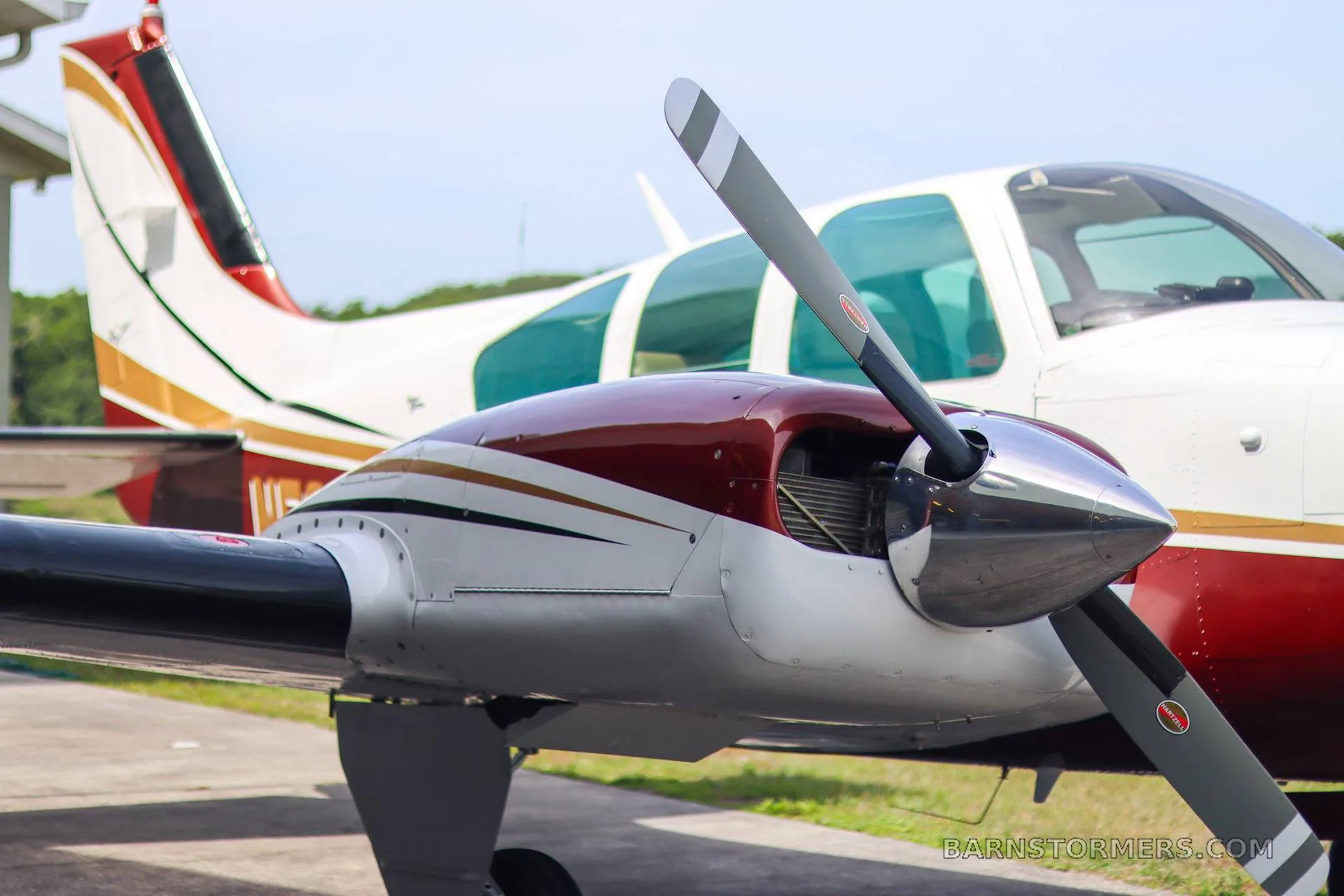 A close-up view of the right engine and propeller of a white and maroon twin-engine aircraft.
