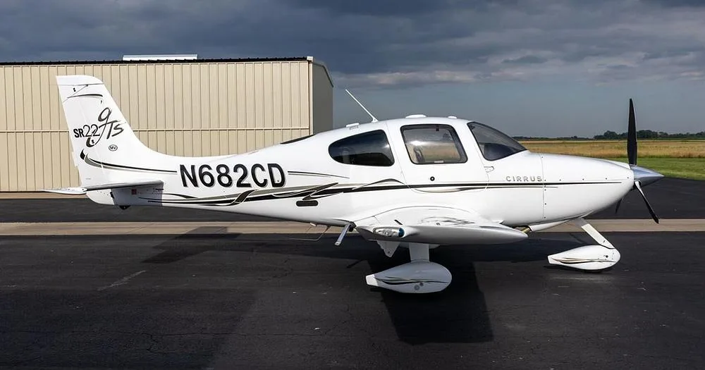 A side view of a white Cirrus SR22T aircraft with black and gold accents, registration N682CD, parked on an airfield.