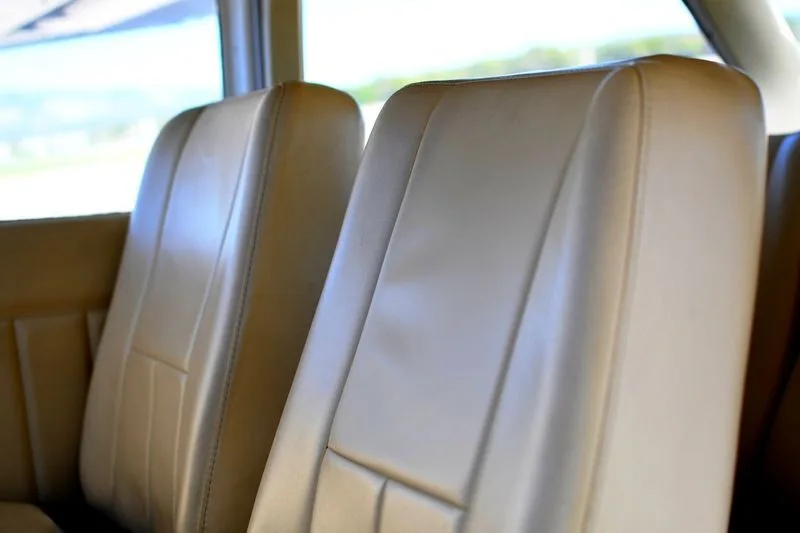 Two light brown leather aircraft seats in the cabin, seen from the rear.