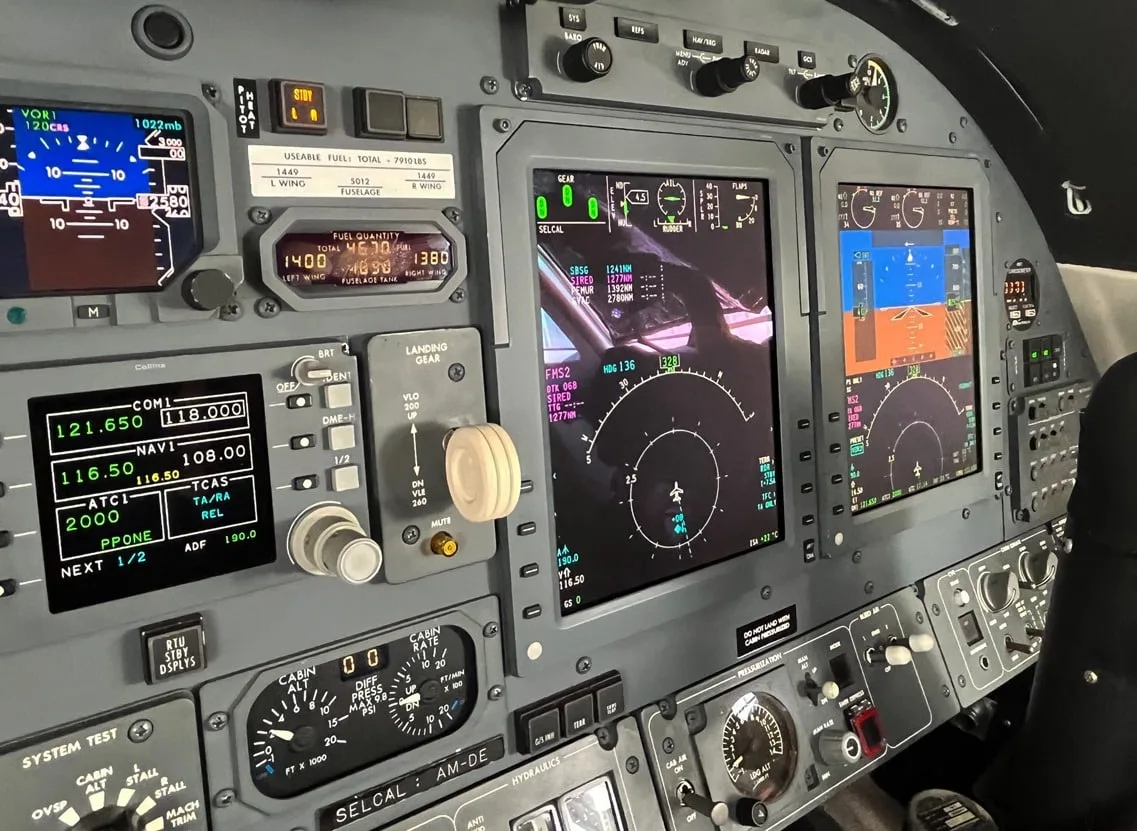 A close-up view of a business jet's instrument panel, showing various digital displays and controls.