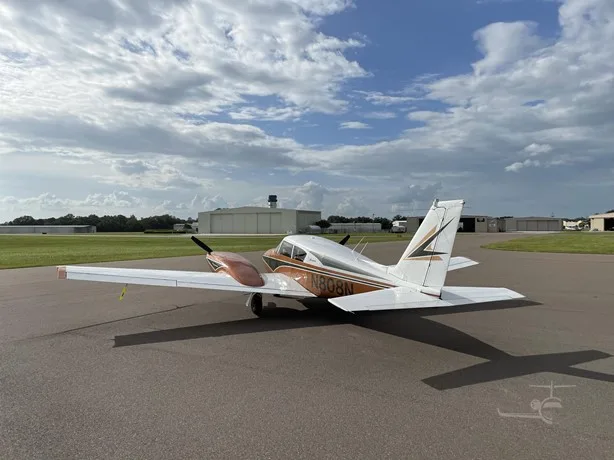 Rear three-quarter view of a copper and white Piper Comanche twin-engine aircraft with registration N808N on an airfield.