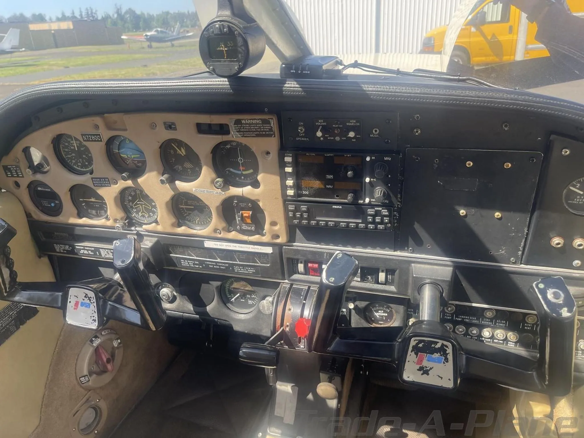 View of the aircraft's cockpit with analog gauges, avionics, and control yokes.